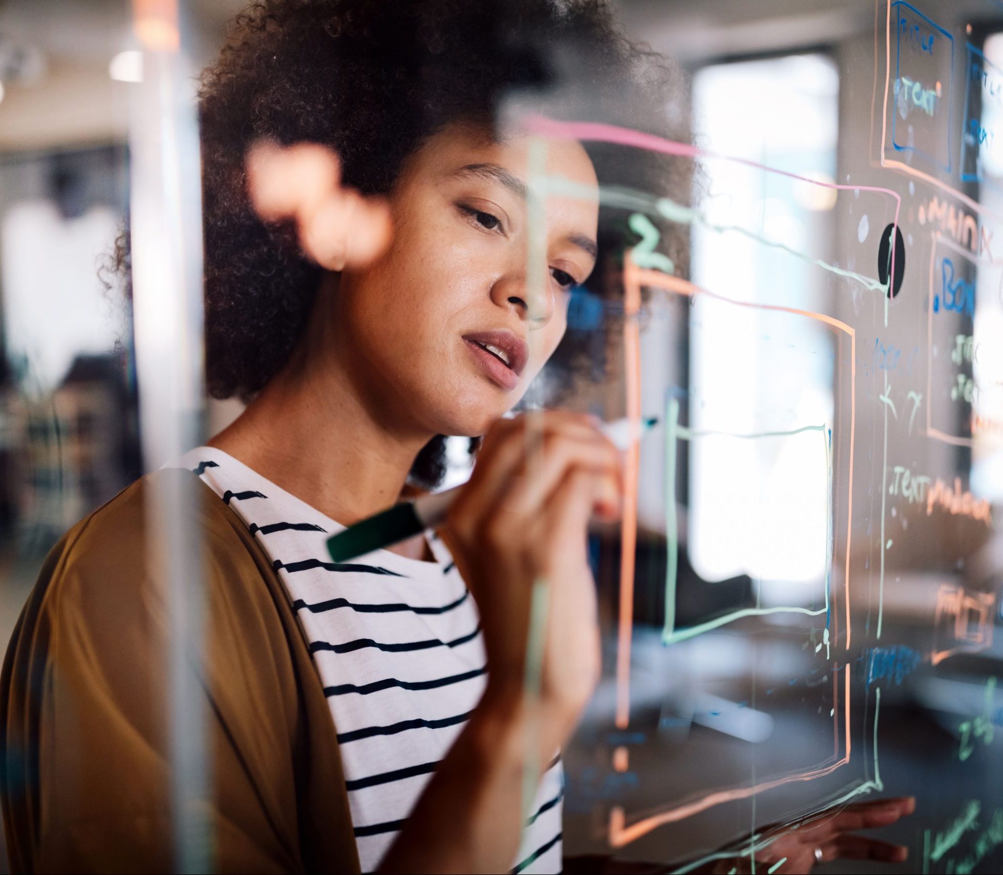 Woman working and writing on the glass board in office. Business, technology, research concept